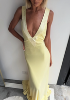 Woman wearing a yellow dress with a plunging neckline on a plain background